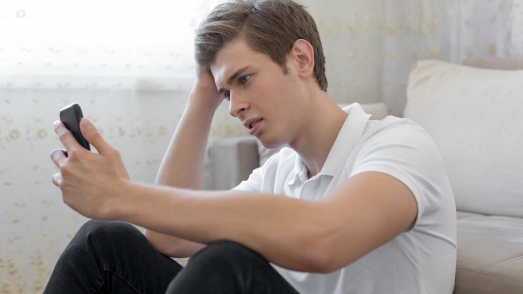 teenage young man distressed looking at phone