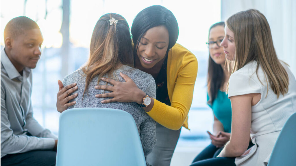 A support group with one participant embracing another