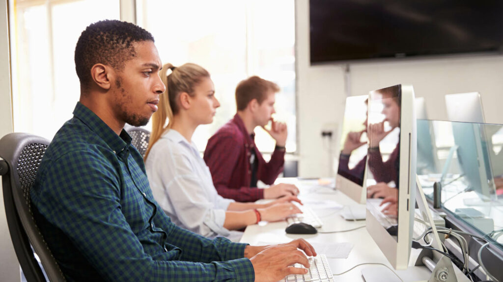 Three people doing research at a row of computers looking thoughtfully