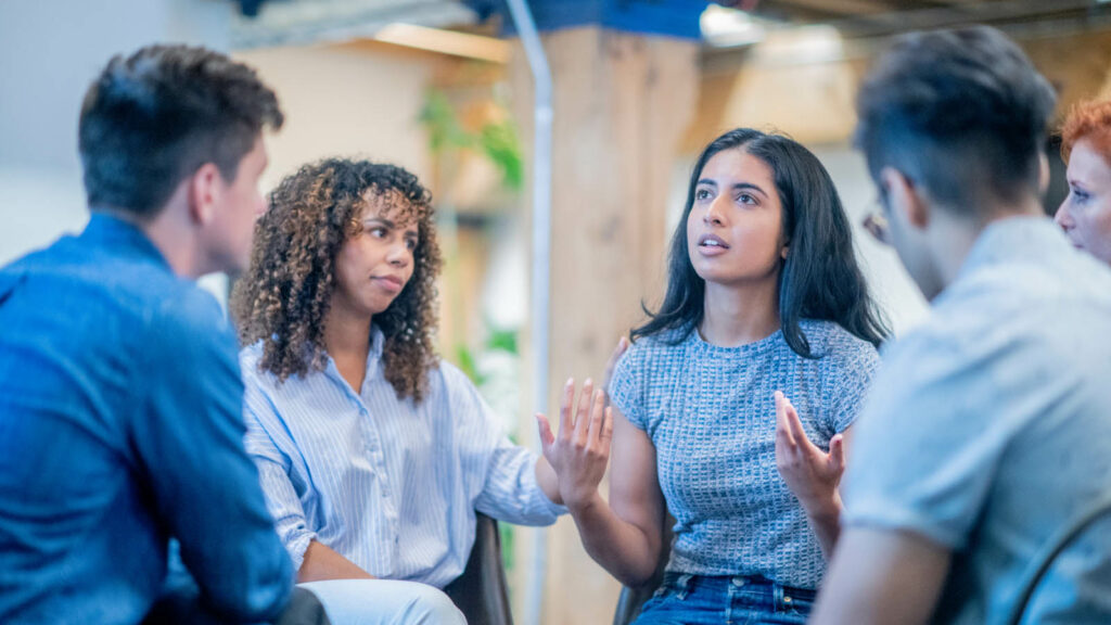 A group therapy session with one person speaking to the group