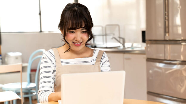 A woman smiling while reading information on a laptop