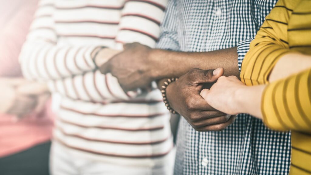 Three adults standing in solidarity with their hands linked