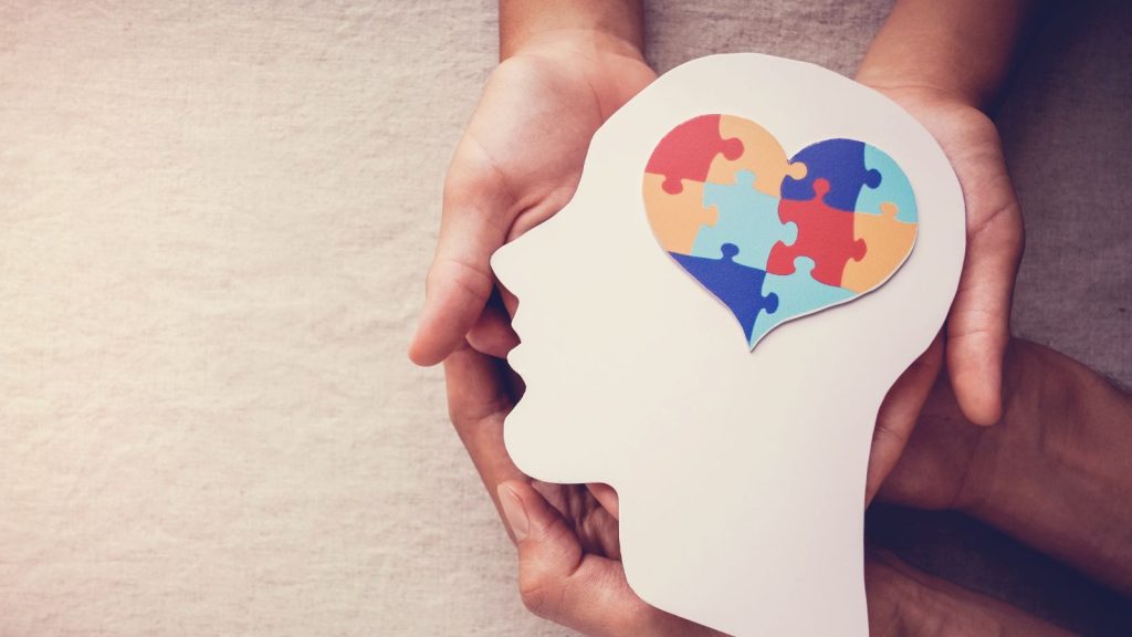 Silhouette of head with puzzle in the shape of heart in brain, symbolizing mental health